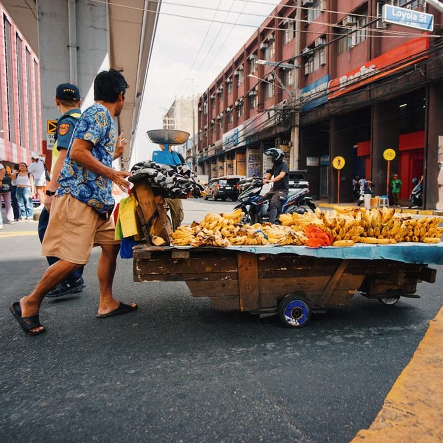 A vendor pushing a fruit cart across a Manila street