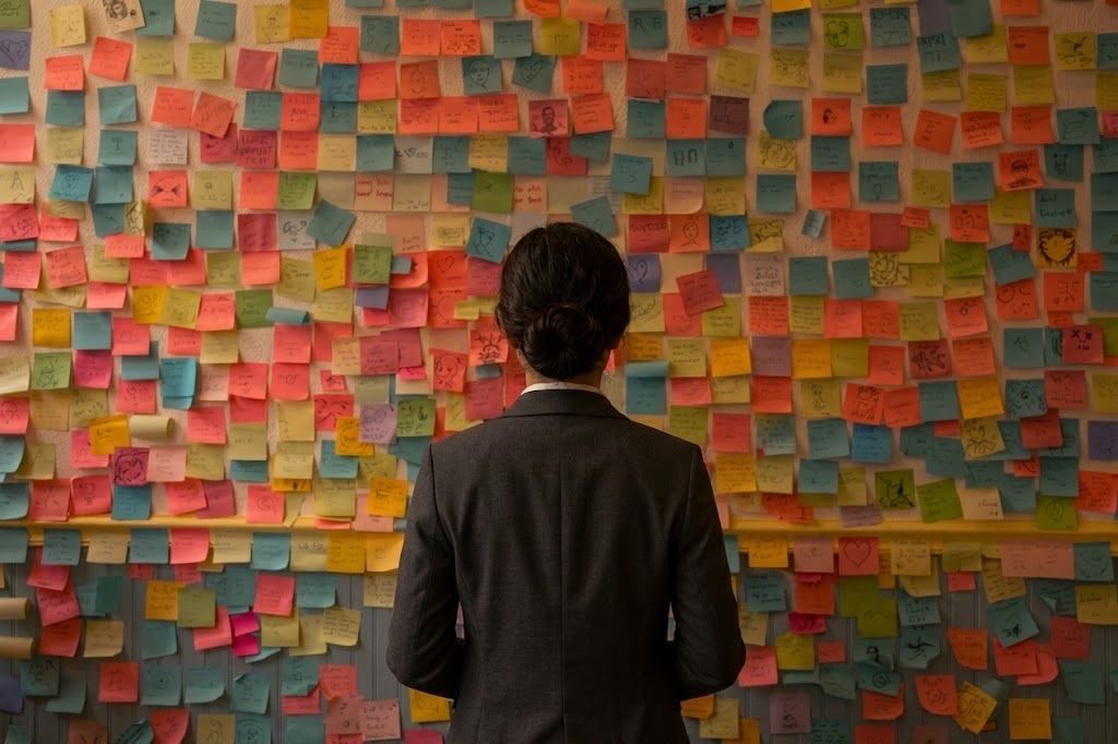 A woman facing a wall covered in hundreds of sticky notes